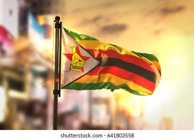 Zimbabwe Flag Against City Blurred Background At Sunrise Backlight 3D Rendering
