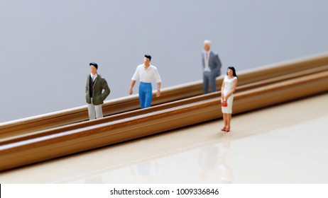 Concept of gender discrimination in the workplace. Miniature men and miniature woman