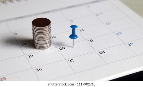 A pile of coins and a blue tack on the calendar.