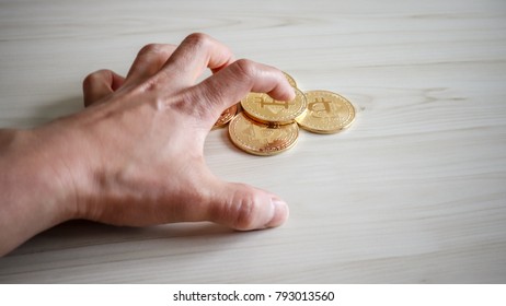 A hand trying to grab a bitcoin strongly.