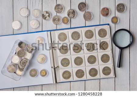 Album with coins and coins in capsules on the table
