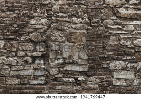 Old grungy retro grimy brick wall of ancient city. Uneven dirty pitted peeled surface brickwork of cellar worn. Ruined solid bumpy stiff blocks. Hard messy ragged holes brickwall for 3D grunge design