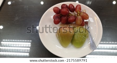 Close​ up​ Grape​ and​ Rose​ a​pple​ pieces​ on​ small​ white​ ceramic​ dish​