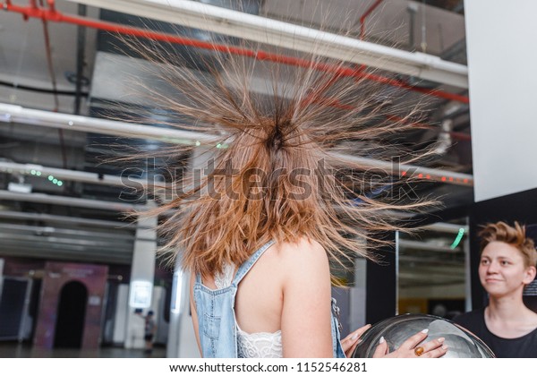 01 JULY 2018,\
UFA, RUSSIA: Portrait of happy woman with standing hair from static\
electricity at physics\
museum