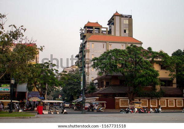 02.16.2018 - Phnom Penh,\
Cambodia: A view of the King Grand Boutique Hotel from Wat Botum\
Park, with motorbikes and tuk tuks parked around the restaurants\
and cafes nearby.