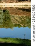 03 Sep 24, Yucaipa Regional Park. Single fishing pole with bobber floating on the water. While the mountains are reflected off the lake. 