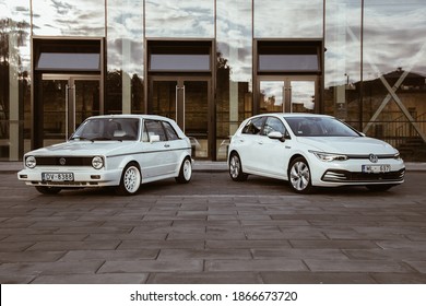 03.06.2020. Riga, Latvia. White Volkswagen Golf mk8 shot together with White Volkswagen Golf mk1 with modern architecture behind.