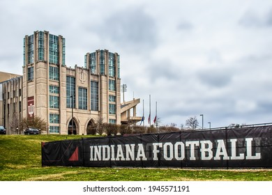 03_26_2021 Bloomington USA - University Of Indiana Hoosier Stadium With Flags At Half Mast Under Cloudy Sky And Sign - Indiana Football - In Foreground