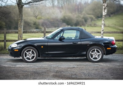 04//04/2020, London, England Beautiful Mazda Miata Mx5 mark mk 2 NB parked up in black colour convertible roof sports car in dirt car park after clean during sunset background with grass country 