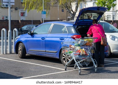 04/09/2020 Portsmouth, Hampshire, UK A Middle Aged Woman Unloading Her Shopping Trolly Full Of Shopping Into The Boot Of Her Car Or Trunk Of Her Car