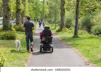 04/18/19 Arundel, West Sussex, UK A woman in an electric wheelchair out for a walk in the park with her partner and service dog
