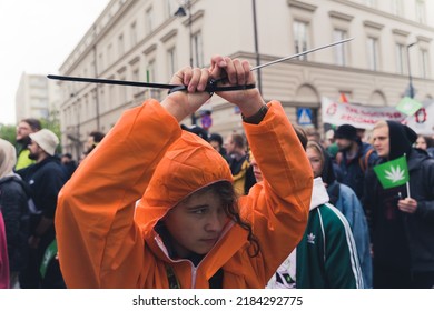 05.28.2022 Warsaw, Poland. Pro-cannabis Protester In Orange Waterproof Jacket Wearing Tie Wrap On Their Wrists To Symbolize Unfair Law. High Quality Photo