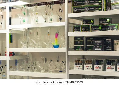 05.28.2022 Warsaw, Poland. White Shop Shelf Full Of Medical Cannabis Related Products. Rolled Joints Of CBD CBG Marijuana, And Glass Bongs In Various Sizes And Shapes. High Quality Photo