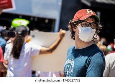 05-30-2020 Tulsa USA - Man In Classes And Cap And Legal Aid Bureau Tee-shirt Glances Backward With Blurred Protesters At BLM Rally Behind Him