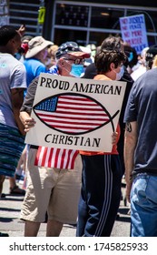 05-30-2020 Tulsa USA - Older Man In Stars And Stripes Hat With Covid-mask Hold Up Sign Reading Proud American Christian In Crowd Of BLM Protestors With Blurred Crowd Behind