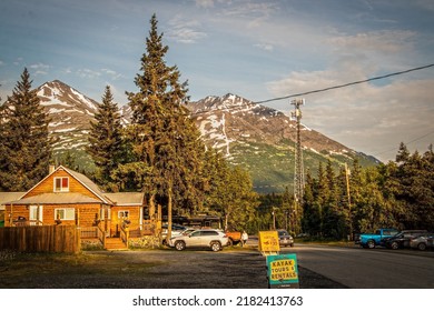 06-24-2022 Moose Pass Alaska USA - Home And Business In Moose Pass On The Kenai Peninsula Taken Late In Evening During Evening Sun Days Of Summer - Kayak And Seaplane Tours Signs - Snowy Mountains 