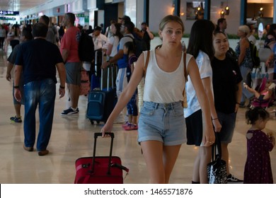 Cancún/Mexico- 06/29/2019: A Young Woman Flying Solo Walks Through A Crowded Terminal At Cancún International Airport