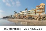 07-14-2021 Carlsbad, California- Beach houses near the rocks sea wall. Oceanside row of beachfront houses with balconies near the shore against the sky background.