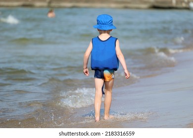 07.19.2022 Rewal, Poland, A Little Boy Is Running On A Sandy Beach By The Water.