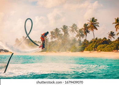 08.17.2019 - Noonu Atoll, Maldives Island Sunset. Professional Fly Board Rider Doing Back Flip With Tropical Resort Island Background. Sunset Sport And Summer Activity Background, Fun Water Sport