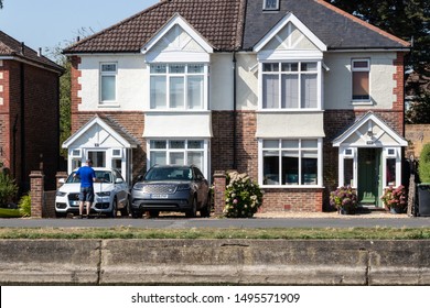 09/02/2019 Emsworth, Hampshire, UK A Man Washing His Car On His Drive Way Using A Hose In Front Of Two Typical English Houses