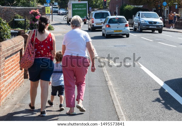 09/02/2019 Emsworth, Hampshire, UK\
three generations walking down the road together including\
grandmother, daughter and grandson with cars and traffic passing by\
