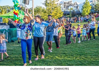 09-25-2021 Tulsa USA - Adults And Children Having Fun Dancing In A Congo Line To Caribbean Music Outdoors In A Park