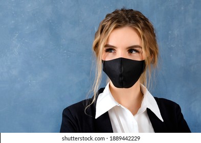 1 european blonde woman in black mask, white shirt and black jacket on gray background close-up, female portrait