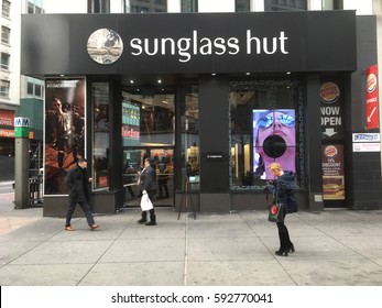 1 February 2017: Woman in winter coats shops and looks at mobile phone in front of Sunglass Hut in Midtown Manhattan on 34th Street near the subway station in New York City.