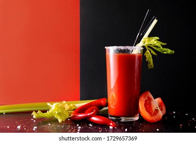 1 glass of tomato juice with fresh tomatoes, celery, cocktail tubes, red and black background