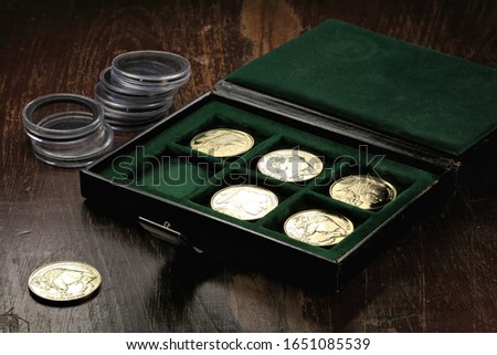 1 ounce American Buffalo gold bullion coins in a coin box on wooden background
