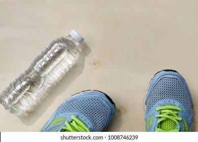 1 Pair Of Blue Sneakers And 1 Bottle Of Water. Placed On A Light Brown Wood Floor. Concept: Sports ,Fitness , Running ,Health  And Exercise. Zumba Dance Workout For Weight Loss.