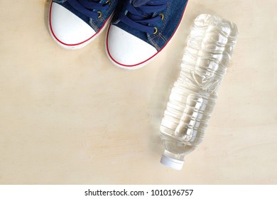 1 Pair Of Blue Sneakers And 1 Bottle Of Water. Placed On A Light Brown Wood Floor. Concept: Sports ,Fitness , Running ,Health  And Exercise. Zumba Dance Workout For Weight Loss.