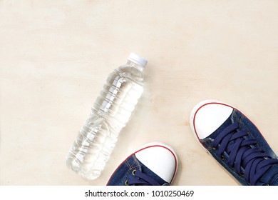 1 Pair Of Blue Sneakers And 1 Bottle Of Water. Placed On A Light Brown Wood Floor. Concept: Sports ,Fitness , Running ,Health  And Exercise. Zumba Dance Workout For Weight Loss.