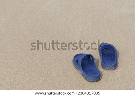 1 pair of sandals on the sandy beach.