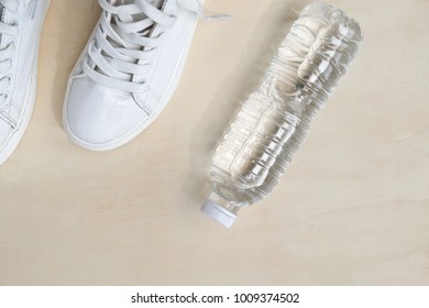 1 Pair Of White Sneakers And 1 Bottle Of Water. Placed On A Light Brown Wood Floor. Concept: Sports ,Fitness , Running ,Health  And Exercise. Zumba Dance Workout For Weight Loss.