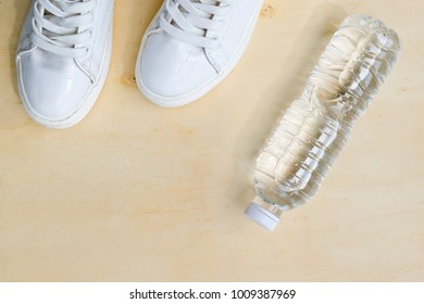 1 Pair Of White Sneakers And 1 Bottle Of Water. Placed On A Light Brown Wood Floor. Concept: Sports ,Fitness , Running ,Health  And Exercise. Zumba Dance Workout For Weight Loss.