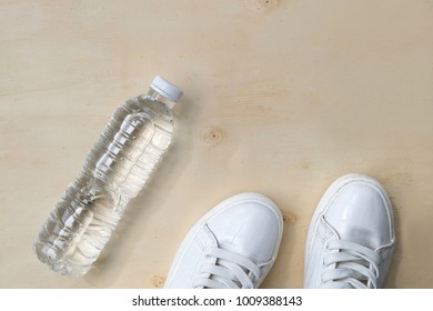 1 Pair Of White Sneakers And 1 Bottle Of Water. Placed On A Light Brown Wood Floor. Concept: Sports ,Fitness , Running ,Health  And Exercise. Zumba Dance Workout For Weight Loss.