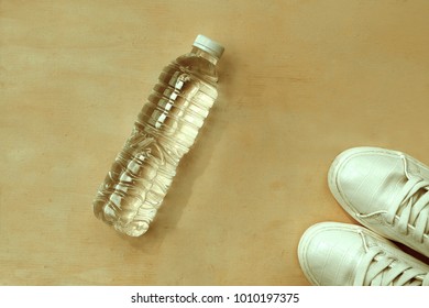 1 Pair Of White Sneakers And 1 Bottle Of Water. Placed On A Light Brown Wood Floor. Concept: Sports ,Fitness , Running ,Health  And Exercise. Zumba Dance Workout For Weight Loss.