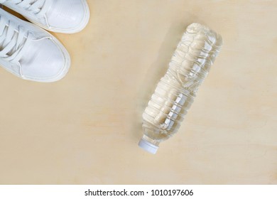 1 Pair Of White Sneakers And 1 Bottle Of Water. Placed On A Light Brown Wood Floor. Concept: Sports ,Fitness , Running ,Health  And Exercise. Zumba Dance Workout For Weight Loss.