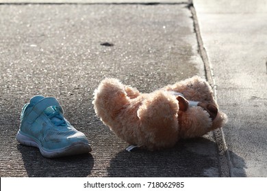 1 Side Of Little Girl Shoe And Her Doll Were Left Or Fall Off On The Road.Nobody,girl Was Disappeared,only Small Blue Shoe And Doll Are Remain.Concept Of  Missing And Exploited Children,lose Child