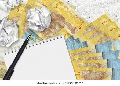 1 Ukrainian hryvnia bills and balls of crumpled paper with blank notepad. Bad ideas or less of inspiration concept. Searching ideas for investment - Shutterstock ID 1804820716
