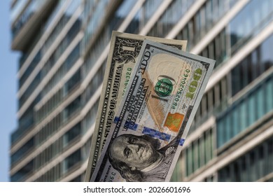 1 USD and 100 USD banknotes against the background of a modern high-rise building