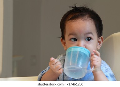 1 Year Old Asian Toddler Boy Wearing Blue Shirt,smart ,clean And Gentlemen Looks. Hold His Drink Or Sippy Cup And Lift It Up To Drinking ,child Can Use A Training Cup Whenever You Think He's Ready. 