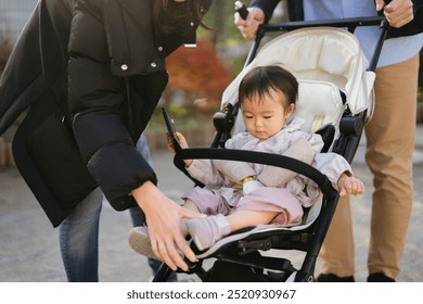 1 year old baby girl in a stroller being put on shoes by her mother - Powered by Shutterstock