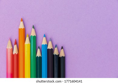 10 coloured pencils arranged haphazardly on a purple, mauve, magenta background - Powered by Shutterstock