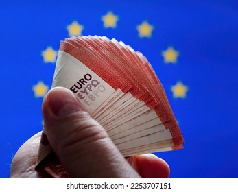 10 Euro Bills in the male hand in front of EU Flag Background as Concept Idea - Shutterstock ID 2253707151