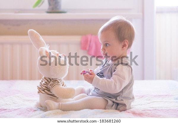 10ヶ月の赤ちゃんの女の子がプラッシュおもちゃと交流する の写真素材 今すぐ編集