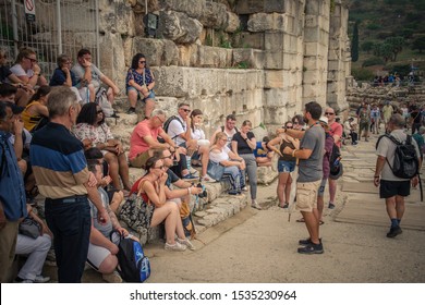 10 October 2019, Kuzadasi Turkey, Tourists Siting And Listing A Tour Guide Explain History  In An Ancient City