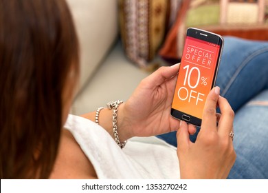 10 Off Promotion, Special Offer In A Cell Phone. One Young Woman In Her Home Resting In Sofa Holding A Smartphone With A Advertising 10% Off  In The Screen.